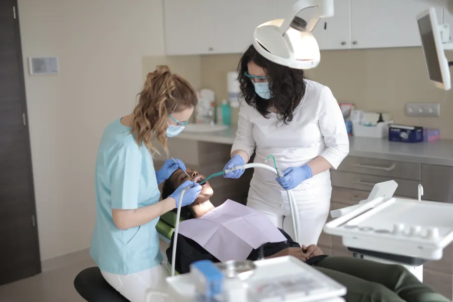 Dentista e assistente examinando os dentes de uma paciente