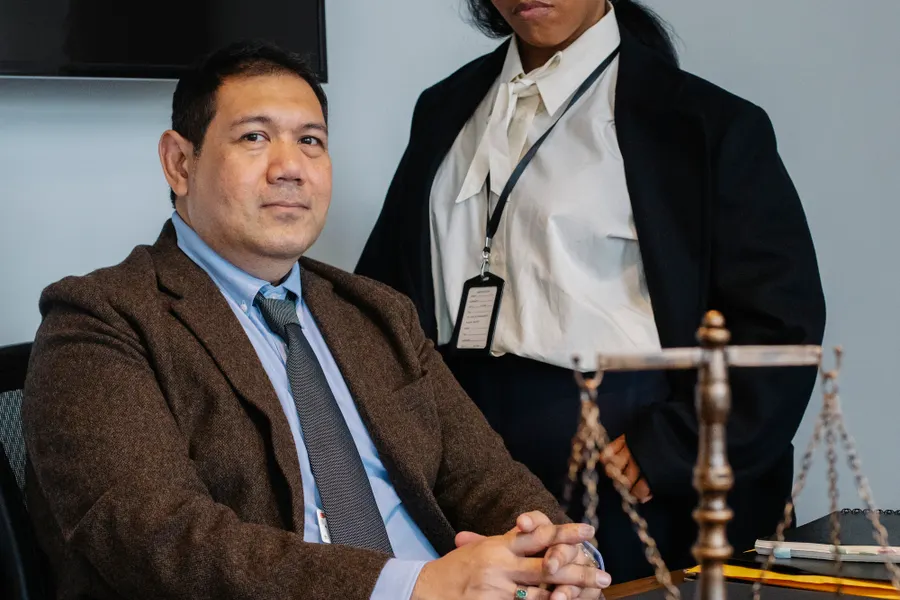 Advogados reunidos em mesa de reunião analisando documentos ao lado da balança da justiça