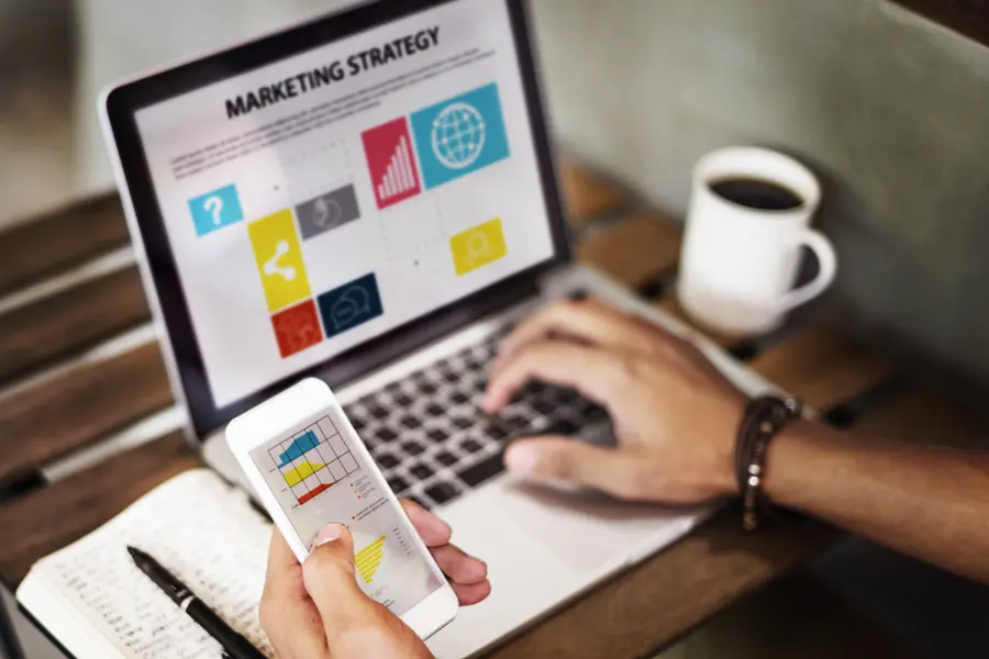 Laptop e celular exibindo painéis de estratégia de marketing