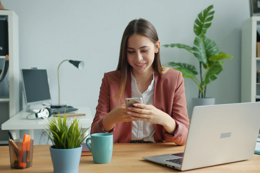 Mulher sorrindo enquanto atende um cliente pelo celular na mesa de trabalho